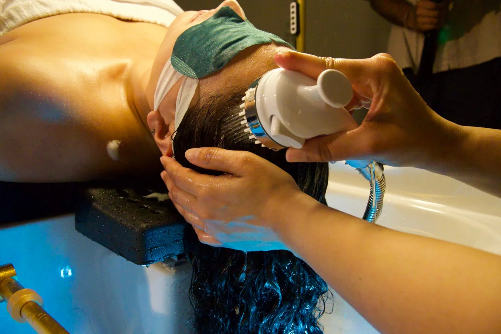 Practitioner using a Japanese head spa massage device at the basin