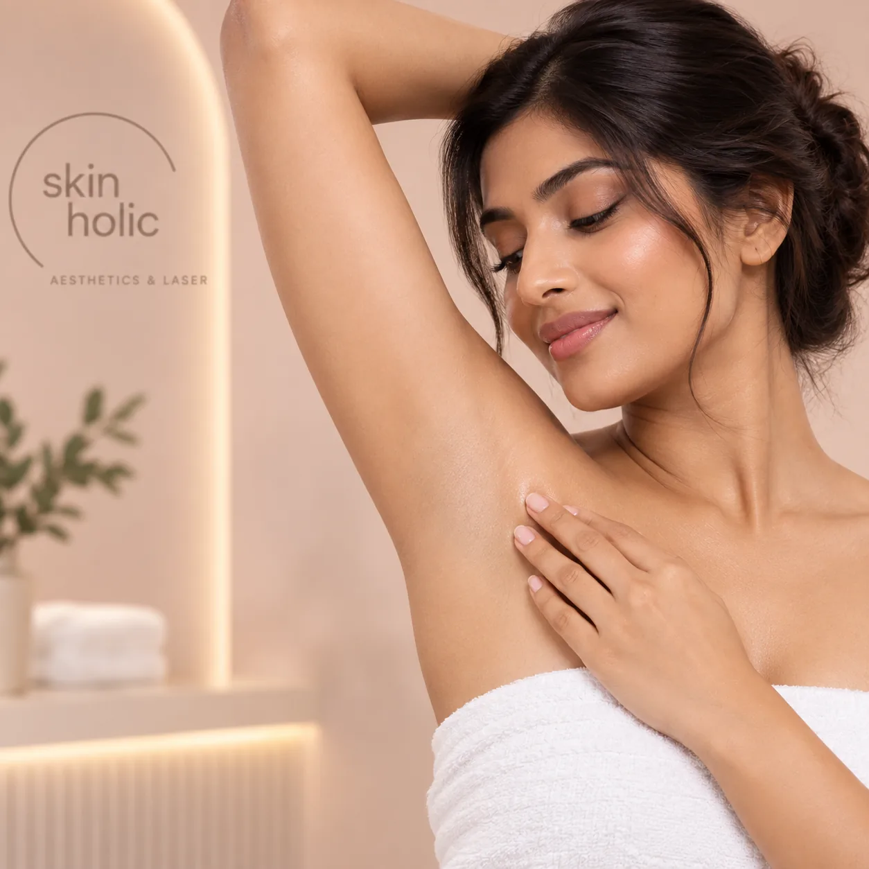 Smiling woman in a white towel touches her smooth underarm in a softly lit spa room, illustrating intimate brightening